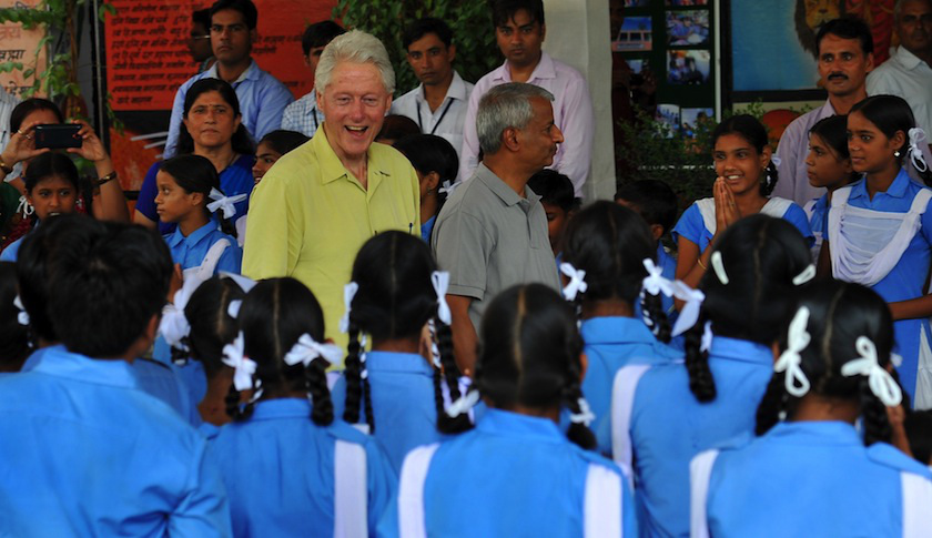 Former US president Bill Clinton (C) smiles as he speaks with Indian schoolchildren during a visit in Sanganer on July 16, 2014. Clinton is on a five-country tour through Asia, visiting projects that work in conjunction with the Clinton Foundation. AFP PHOTO / STR (Photo credit should read STRDEL/AFP/Getty Images)