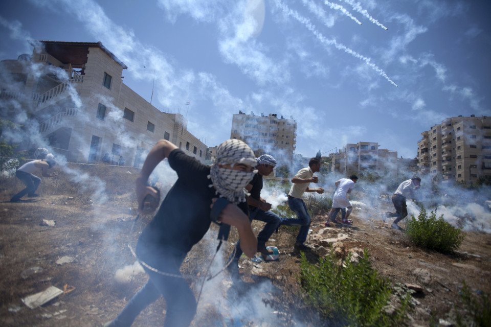 Palestinians run for cover during clashes with Israeli soldiers following a protest against the war in the Gaza Strip, outside Ofer, an Israeli military prison near the West Bank city of Ramallah, Friday, Aug. 1, 2014. (AP Photo/Majdi Mohammed)
